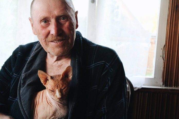 Ένας ηλικιωμένος άνδρας αγκαλιά με τη γάτα του (Photograph by Veronika Tarasova)