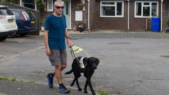 Ο Τζον Πέτι και ο σκύλος-οδηγός του, Ντίξον (Photo: Joanne Stone)